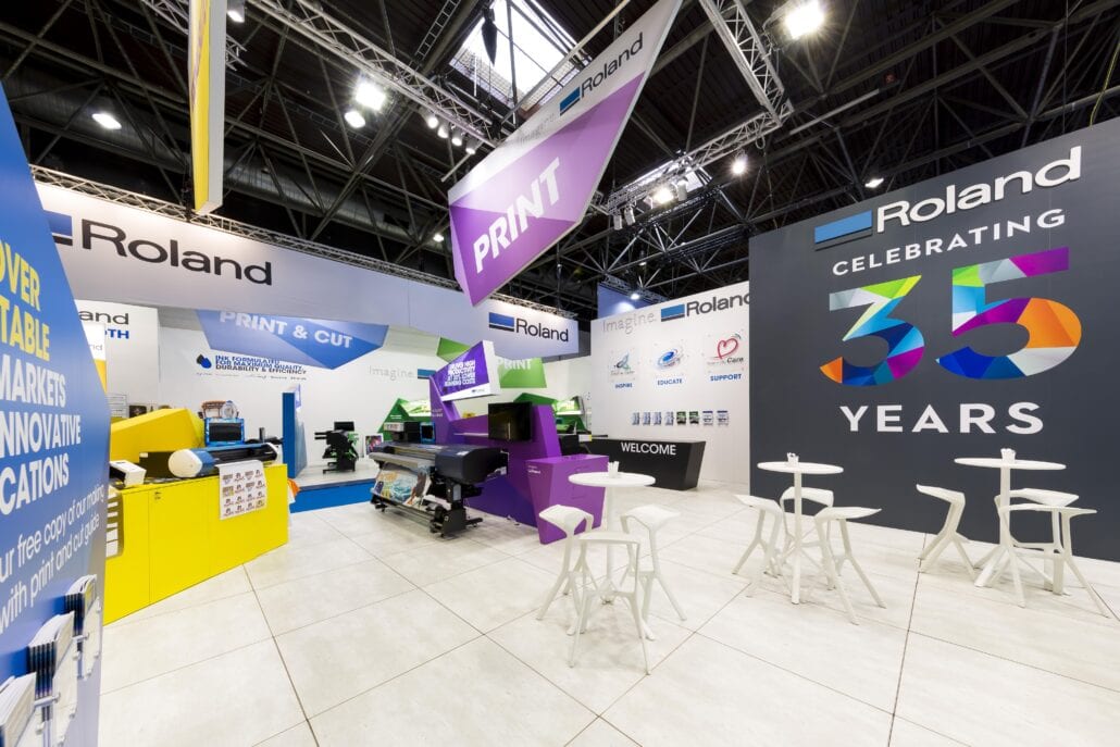 In het ontwerp werd zelf het meubilair op maat gekozen bij de vormentaal van de beursstand. Bij Expo Z gaan we voor de perfectie en elk detail telt! beursstand Roland DG met zicht op de receptietafels waar de klanten ontvangen worden